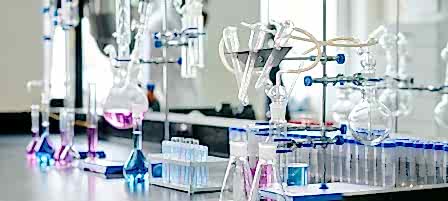 Two empty beakers standing next to glassware equipment for chemical experiments on workplace of biotechnologist or scientist