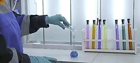 Woman conducts laboratory experiments and analyzes. Clip. Woman looks at chemical liquid in laboratory. Industrial laboratory with workers and chemicals in test tubes.